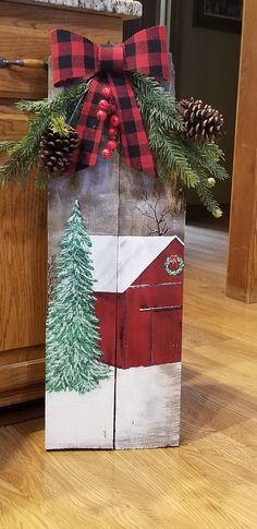 a wooden block decorated with pine cones and a red barn painted on it's side