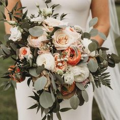 a bride holding a bouquet of flowers and greenery