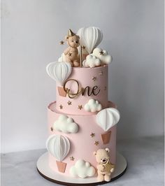 a three tiered pink cake with balloons and teddy bears on top, one is for the first birthday girl