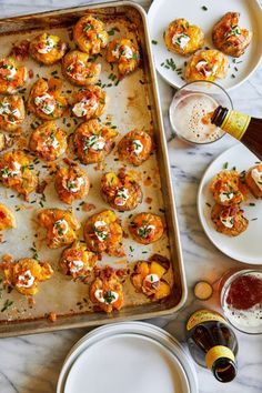 a pan filled with food on top of a table next to plates and glasses full of beer