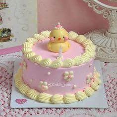 a pink cake with a yellow rubber ducky on top and white icing around the edges