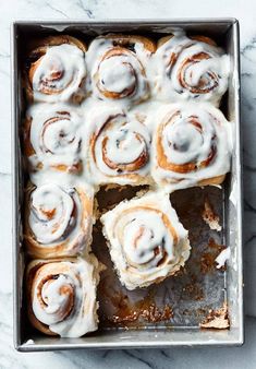 a pan filled with cinnamon rolls covered in icing