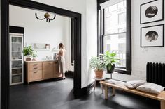 a woman is standing in the kitchen looking into the living room through an open door