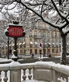 a stop sign covered in snow next to a street with buildings and trees on both sides