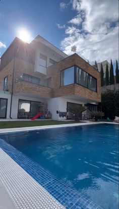 a house with a swimming pool in front of it and the sun shining through the windows