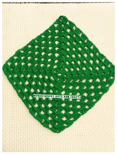 a green crocheted square on top of a white blanket