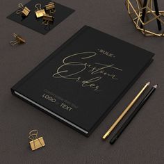 a black and gold wedding guest book surrounded by stationery items, such as pen, paperclips, and pens