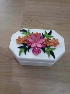 a white box with flowers on it sitting on a wooden table next to a pair of scissors