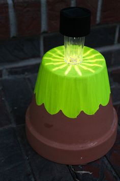 a green and red light sitting on top of a wooden table next to a brick wall