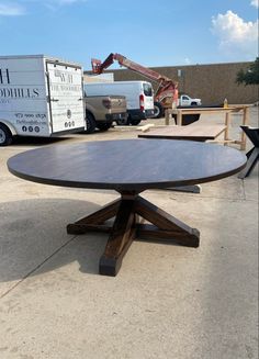 a wooden table sitting in the middle of a parking lot next to other trucks and construction equipment