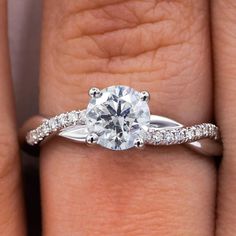 a woman's hand with a diamond ring on top of her finger and the engagement band