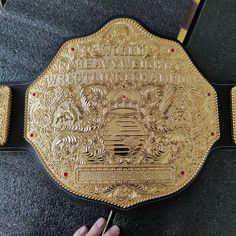 a person is holding up a gold wrestling belt