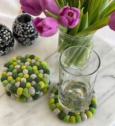 a vase filled with purple and green flowers next to two small balls on a table