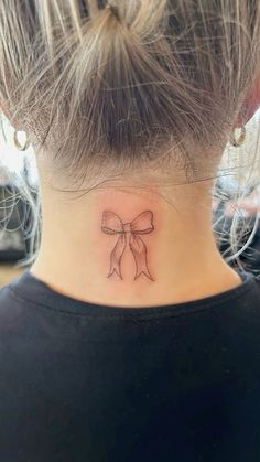 a woman's neck with a bow tattoo on it