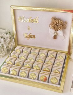 a display case filled with lots of gold colored cookies next to white flowers and ribbons