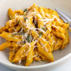 a white bowl filled with pasta and parmesan cheese on top of a table