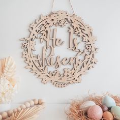 a wooden wreath with the words be present on it next to some eggs and flowers