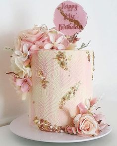 a pink and gold birthday cake decorated with flowers