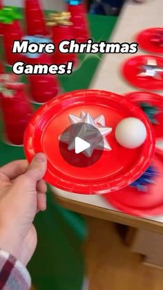 a person holding a red plastic plate with an object on it that says more christmas games