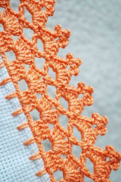 an orange and white piece of cloth with crochet work on the edges that has been stitched together