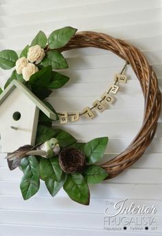 a birdhouse wreath with the word welcome hanging on it's side and flowers