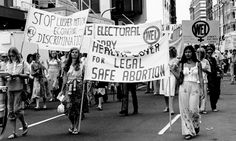 a group of people marching down the street with signs on them and banners in front of them