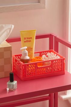 a pink table topped with a container filled with soap and lotion on top of it