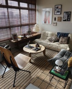 a living room filled with furniture and windows covered in shades of brown, white and blue