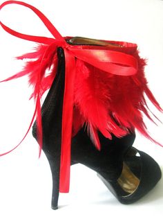 a pair of black high heeled shoes with red feathers