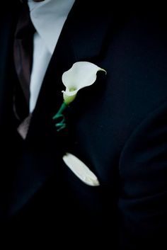 a man in a tuxedo is wearing a boutonniere with a white flower on it