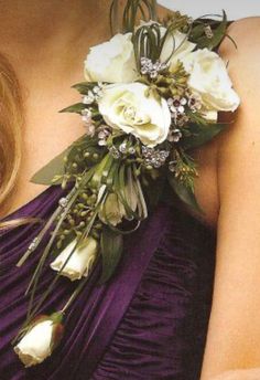 a woman wearing a purple dress holding a bouquet of white roses and greenery in her hand