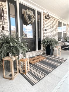 two planters on the front porch of a house with black and white striped rug