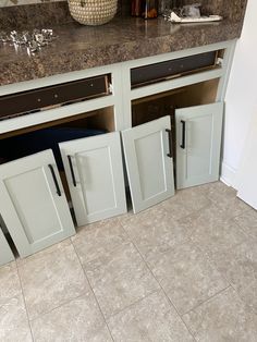 a kitchen with white cabinets and marble counter tops