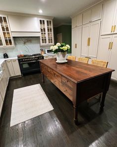 a large kitchen with white cabinets and wooden counter tops, along with an island in the middle