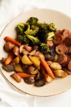 a white plate topped with meat and veggies next to a pile of broccoli