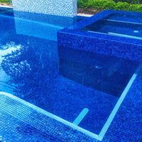 an outdoor swimming pool with blue tiles and water features in the middle, surrounded by greenery