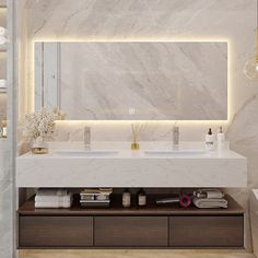 a bathroom with marble walls and white counter tops, along with a large lighted mirror above the sink