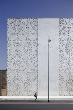 a person walking down the street in front of a white building with intricate designs on it