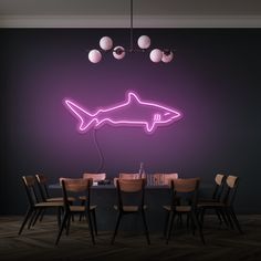 a dining room table with chairs and a neon shark sign on the wall above it