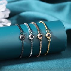 five different bracelets on top of a blue cloth next to a white and black flower