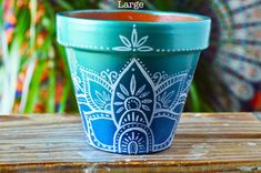 a blue and white flower pot sitting on top of a wooden table next to a plant