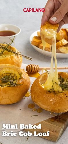 a person dipping cheese on top of bread with honey and rosemary sprinkled over it