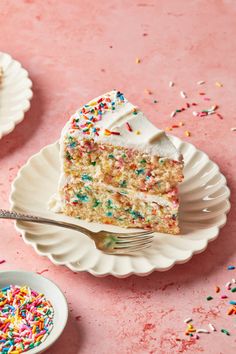 a slice of cake with sprinkles on a white plate next to a fork