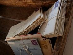 several mail envelopes are stacked on top of each other in an old wooden box