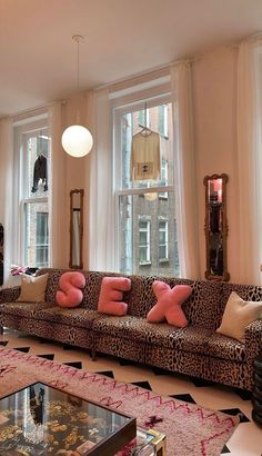 a living room filled with lots of furniture and large windows covered in leopard print curtains