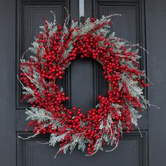 a wreath with berries and greenery hangs on the front door