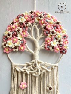 a crocheted tree with flowers hanging from it's sides on a wall