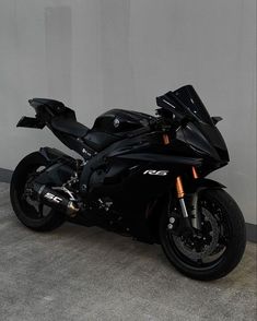 a black motorcycle parked next to a white wall