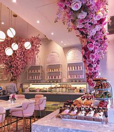 the interior of a pastry shop with pink flowers hanging from the ceiling