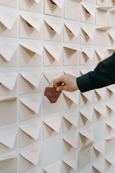 a person writing on a wall covered in post it notes